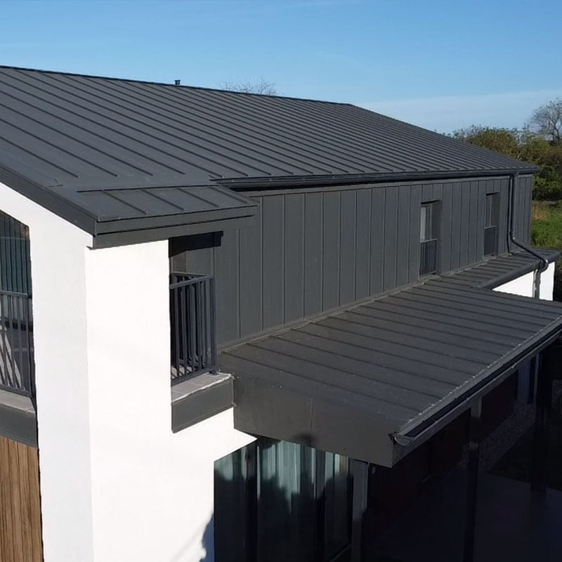 A képen egy antracit korcolt lemezzel fedett családiház látható